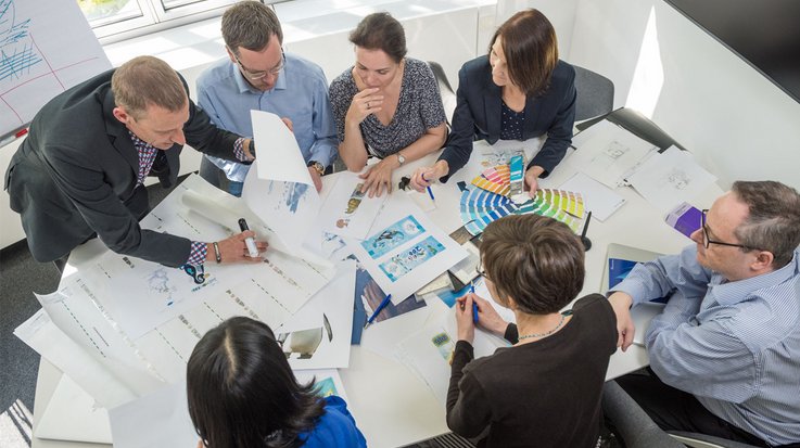 A group of people sits around a table and discusses different designs