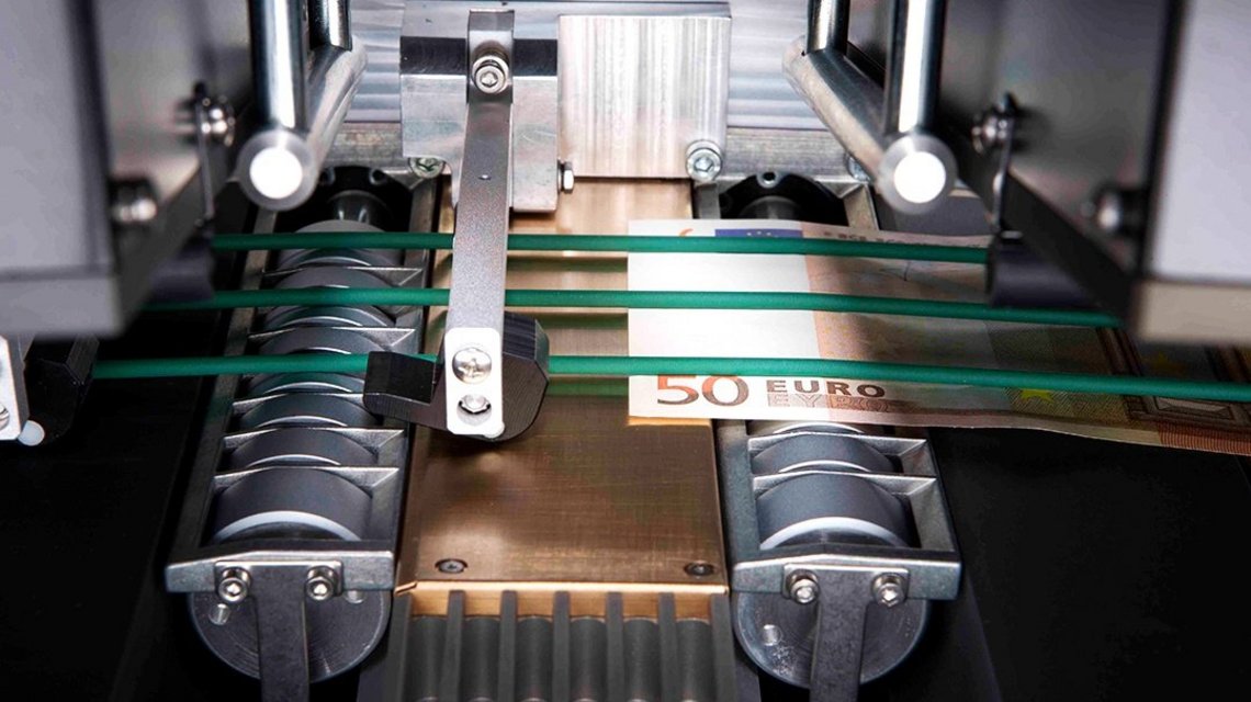 A €50 bill passes through a money counting machine