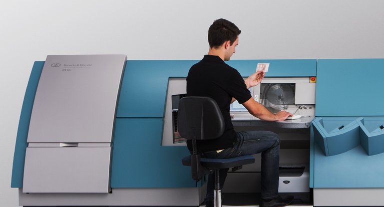 A man sits at the BPS® M5 banknote processing system and takes a close look at a banknote