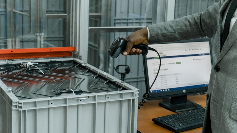 A man holds a scanning device pointed at a large plastic box