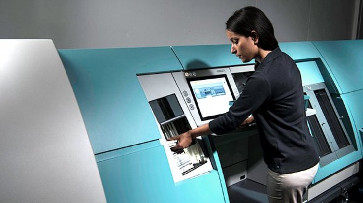 A woman works on a banknote processing system from G+D