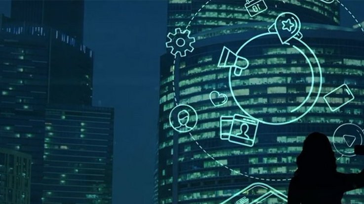 A woman holds up her smartphone, against a big city backdrop at night, various icons light up in front of her