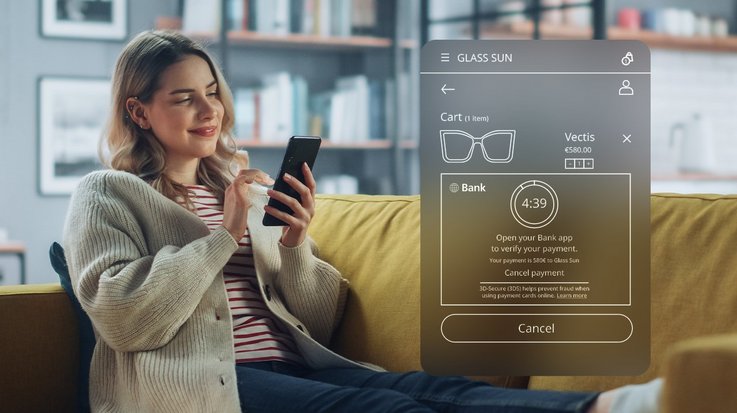 A woman holds her smartphone and confirms an online purchase at her bank