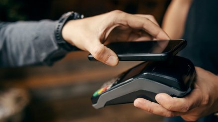 Female hand paying with a mobile phone at a POS