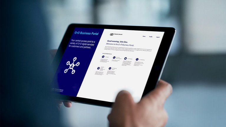 A person holding a tablet displaying the G+D Business Portal, which offers various digital services