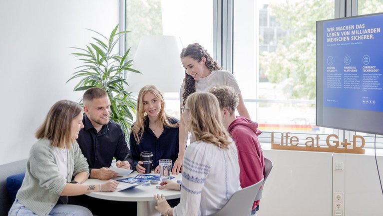 Young people sitting together at a table discussing in an office