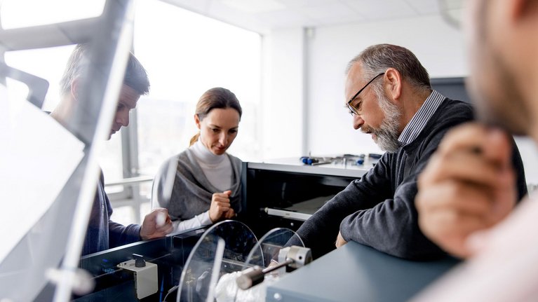 Four men are participating in a training session, working together on a G+D product in an office setting
