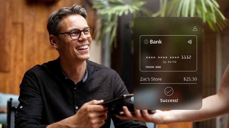 A man completes a contactless payment using a mobile device at an outdoor cafe, with a success message displayed on the payment terminal screen.
