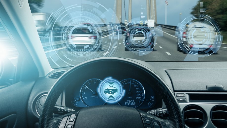 Driver perspective with digital head-up display showing vehicles and driver assistance systems.