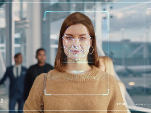 Woman goes through an automated passport border control with a biometric facial recognition scanner