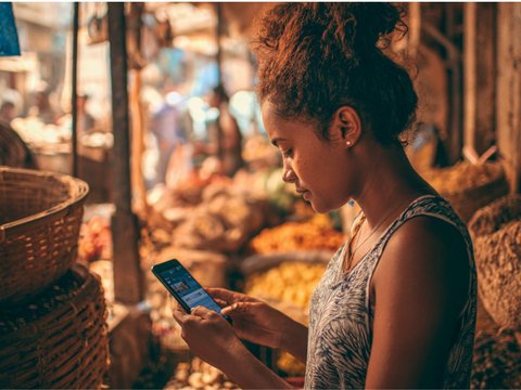 A Brazilian woman uses a CBDC app for making a payment on her smartphone while being at a market.