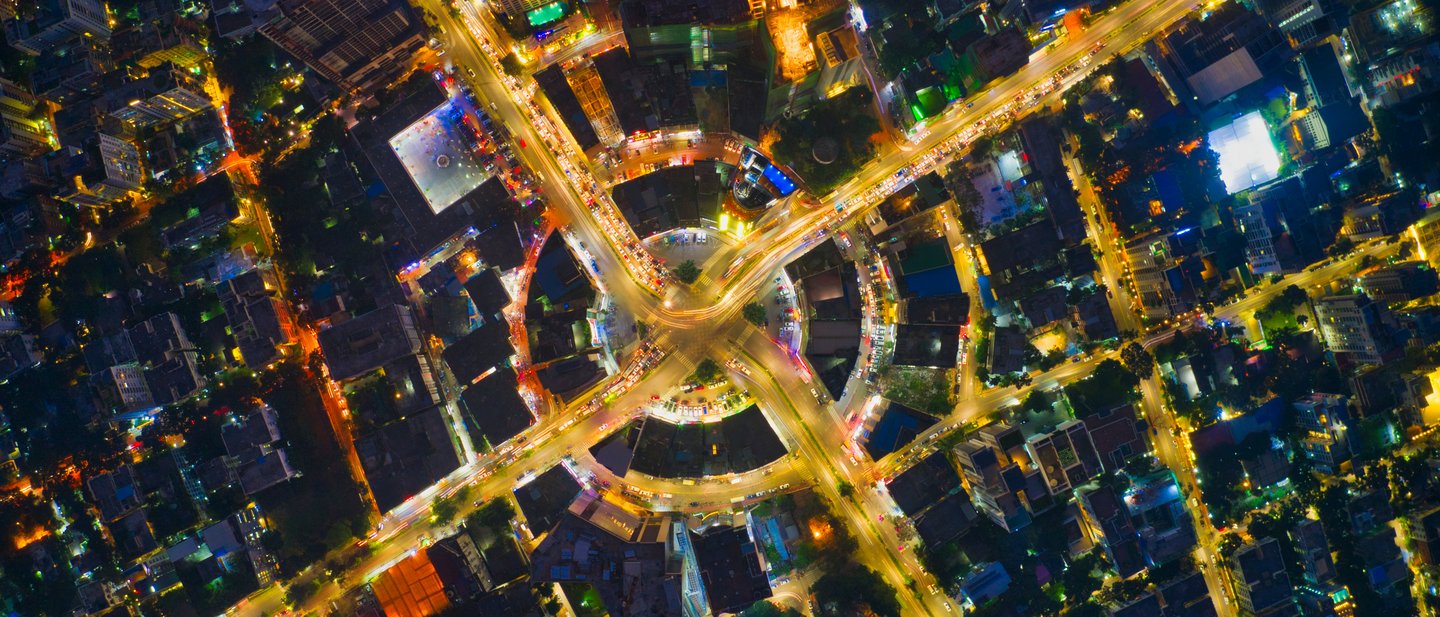 Aerial view of a city intersection at night, showing a traffic circle with radiating roads