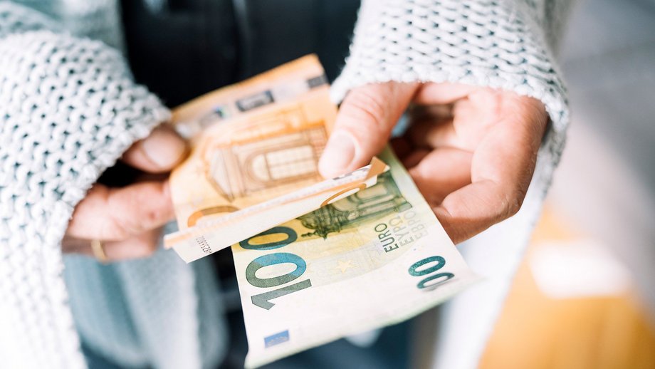 Hands holding euro banknotes.