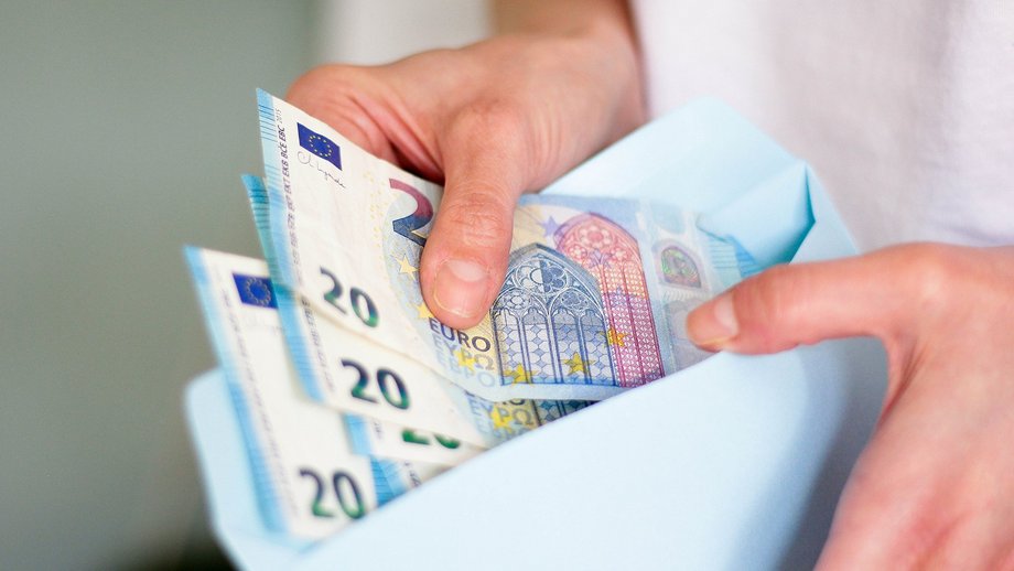 Hands counting twenty-euro banknotes from an envelope