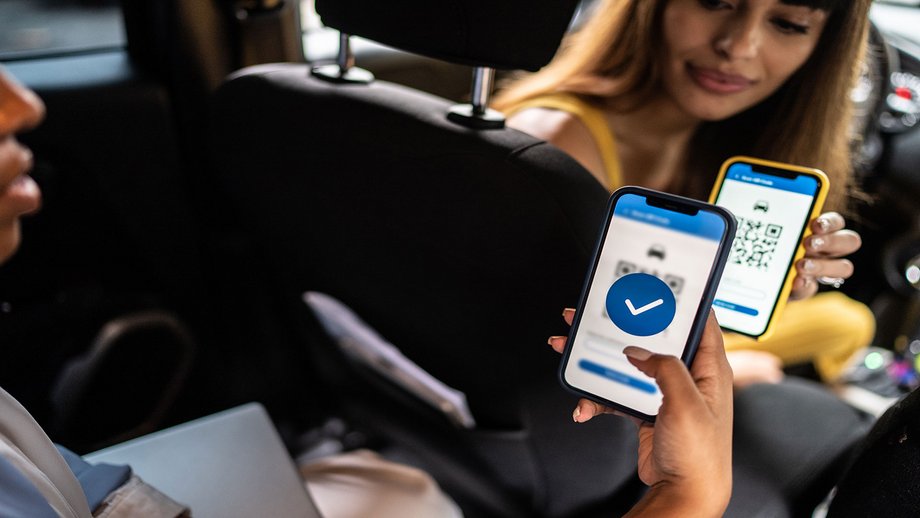 A person uses a QR code to pay a taxi driver for a journey