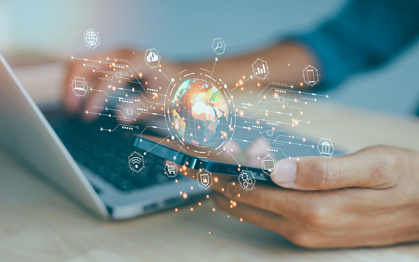 Person using a laptop and smartphone with a digital globe and network icons in the foreground.