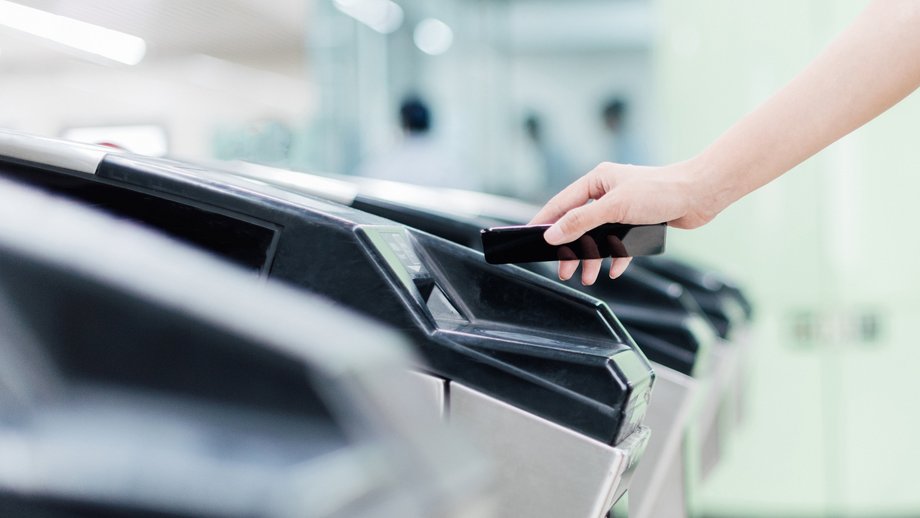 Person using a smartphone for verification at a turnstile.