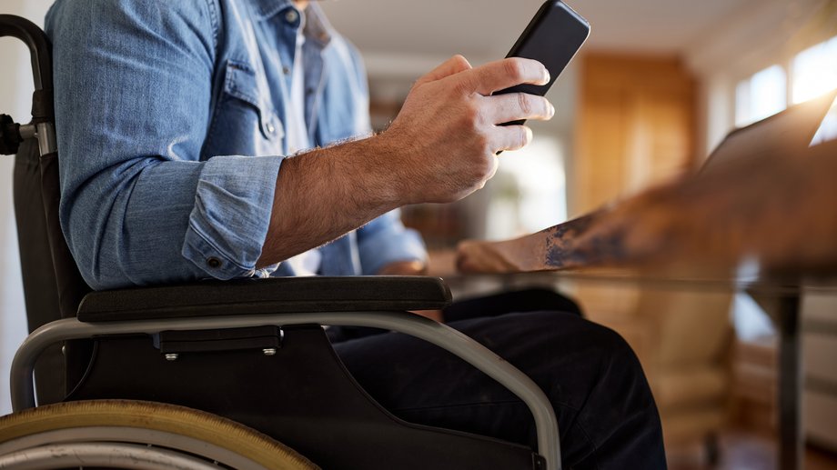 Person in a wheelchair using a smartphone at a table