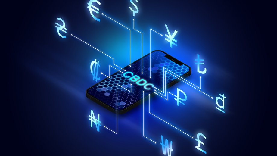 A smartphone displays “CBDC” surrounded by various global currency symbols.