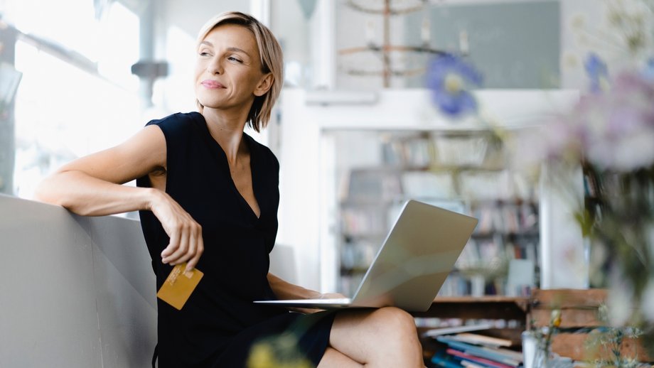Woman with laptop and credit card in modern office