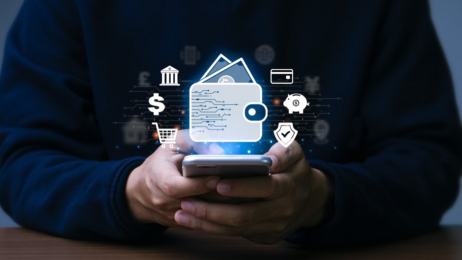 A man is holding his smartphone showing multiple app symbols and a digital wallet symbol.