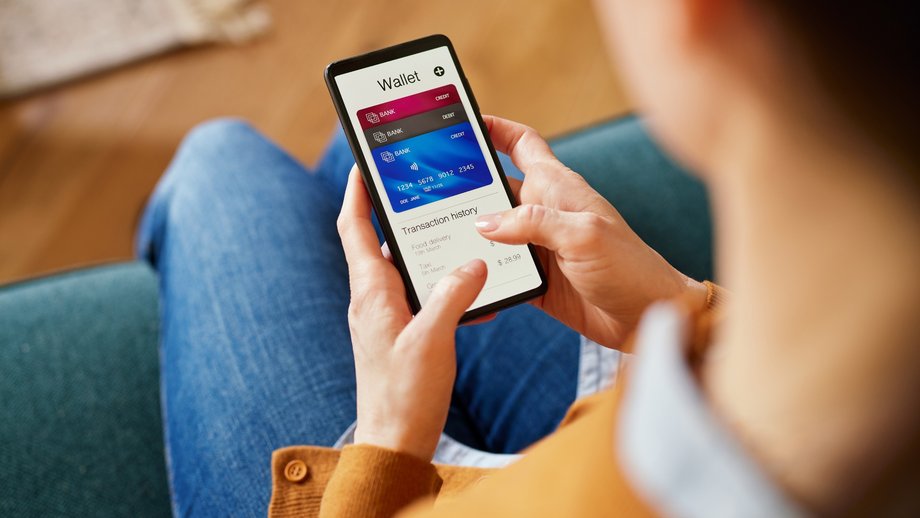 A female customer holding a credit card while paying online via smartphone at home.