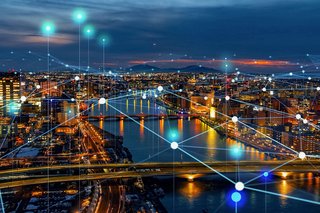 City skyline at night with illuminated network connections symbolizing digital communications