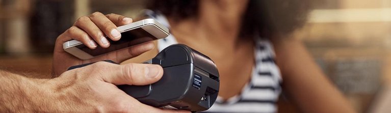 A woman pays contactless with her smartphone in a restaurant
