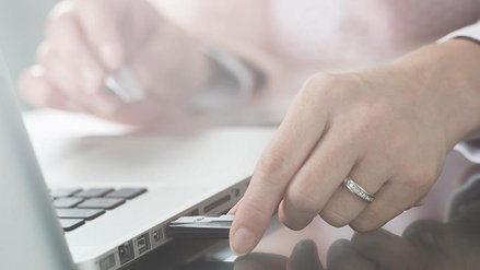 A woman inserts a USB stick into a laptop