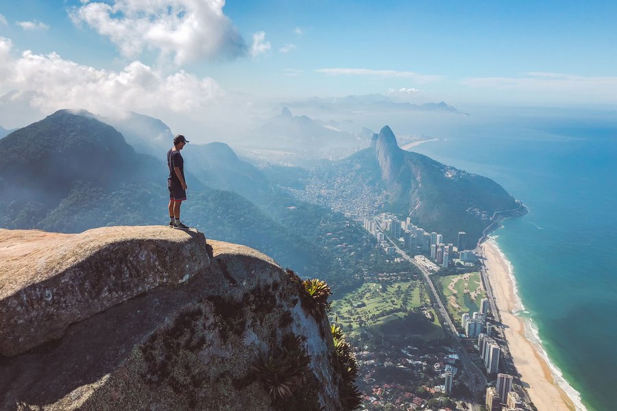 A man stands on the top of Pedra da Gávea watching the views over Rio de Janeiro, Brazil