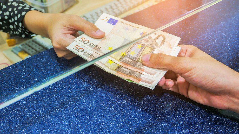 Cash is handed out at a bank counter.