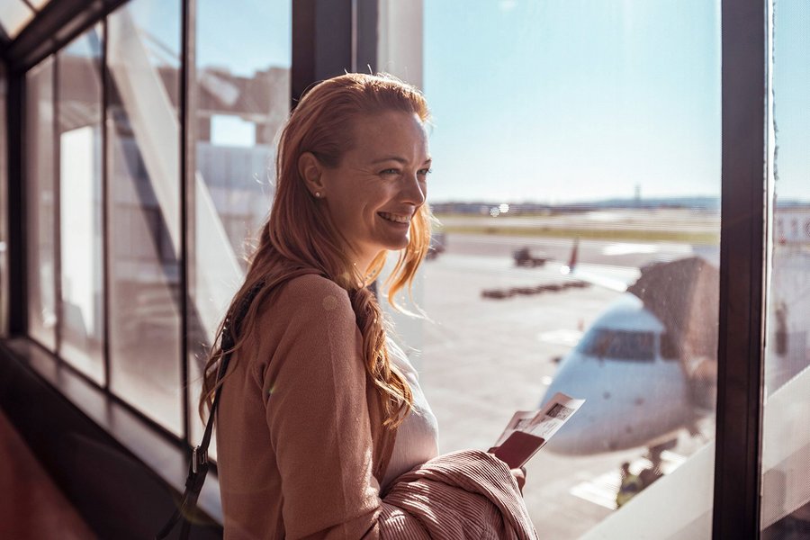 Smiling woman at the airport with a passport