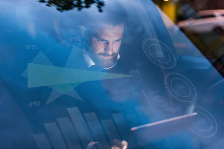 Man sitting in a car using the eSIM technology connected with his car and tablet
