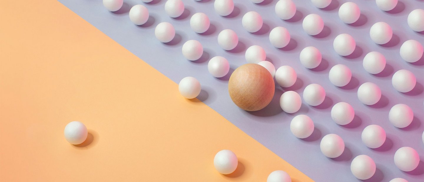 One bigger scale sphere trying to break into an orderly arranged rows of sphere on another side symbolizes how traditional banks have to collaborate with Fintechs.