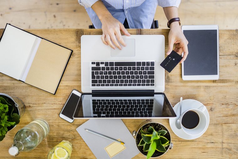 View of woman at desk with credit card and laptop doing online banking