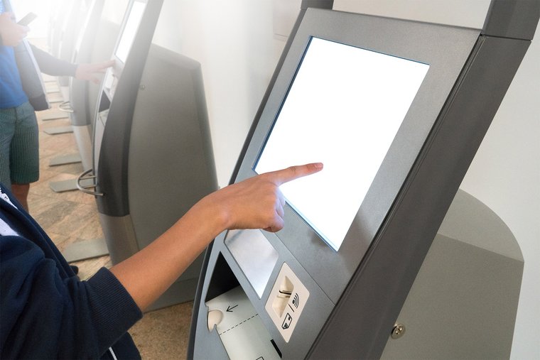 A woman using instant issuance on a kiosk with other customers also using kiosks in the background