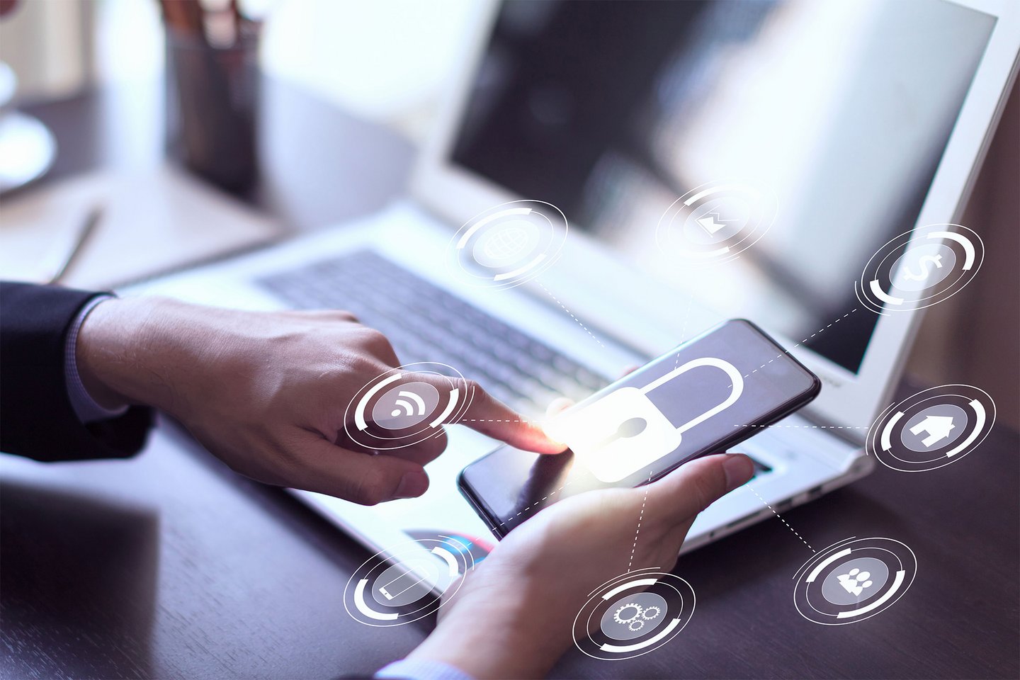 Businessman hand working with mobile phone and laptop computer with technology digital graphic symbolizes cybersecurity.