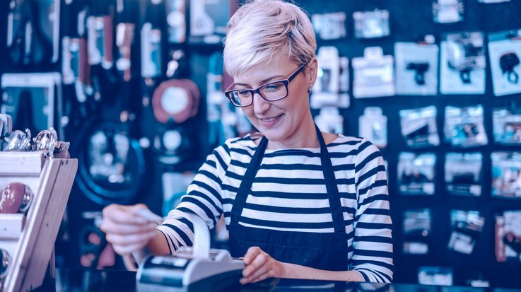 A female employee with short blonde hair and glasses in a retail store