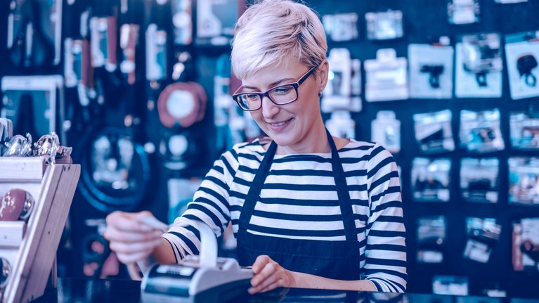 A female employee with short blonde hair and glasses in a retail store