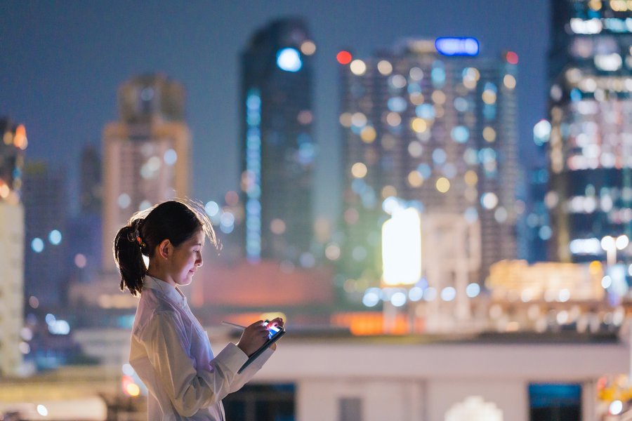 A woman using a tablet in front of the skyline of a city