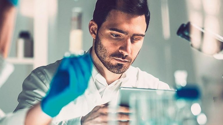 A man in a medical laboratory operates a tablet