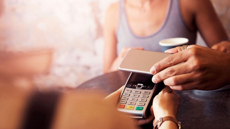 A person pays contactless with the smartphone in a café