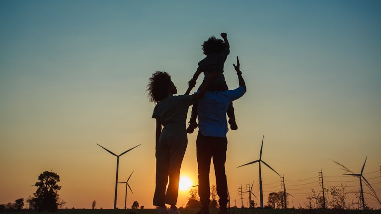 family during sunrise with windmills on the horizon