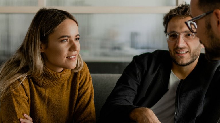 A woman sits opposite another person and listens attentively
