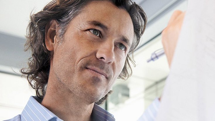 A man with a business shirt notes something on a piece of paper