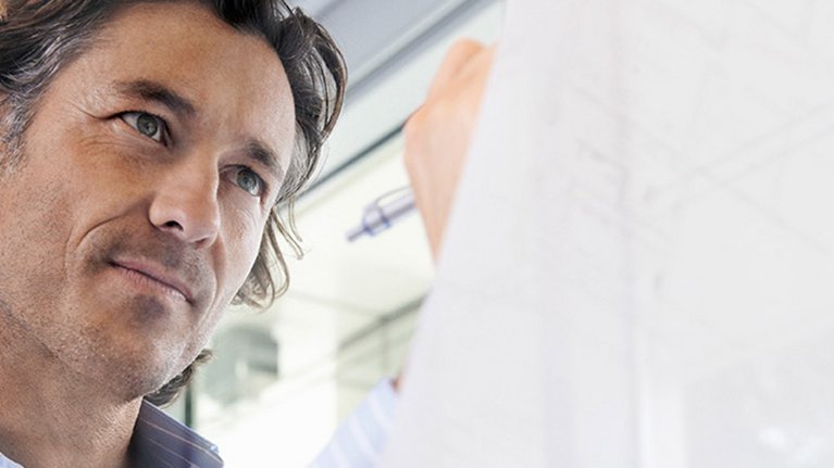 A man with a business shirt notes something on a piece of paper