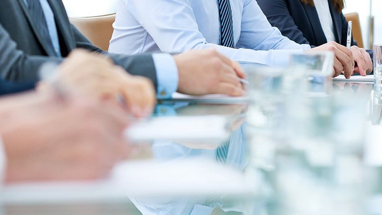 four people sitting at a table and taking notes