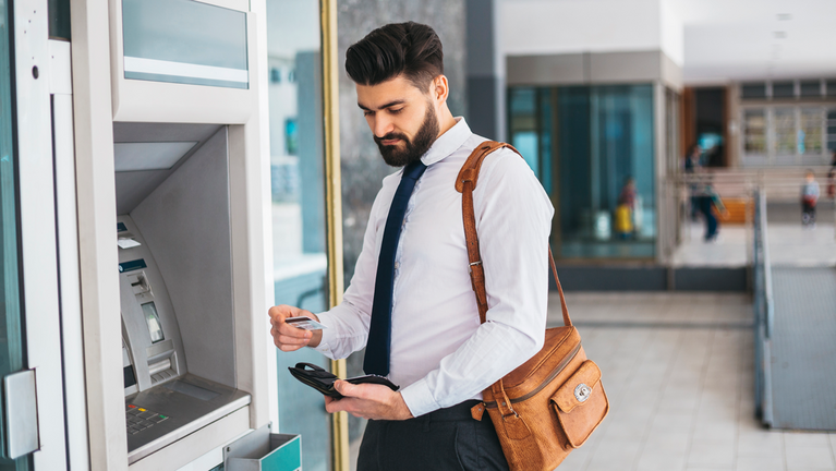 A businessman operates an ATM machine