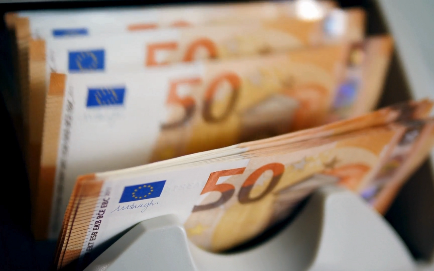 A money counting machine checks, counts, and sorts several 50-euro banknotes